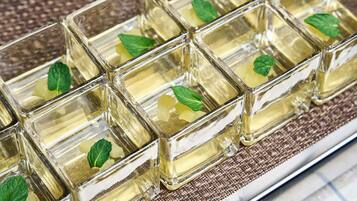 Un vassoio con cubetti di vetro trasparente contenenti un liquido giallo, probabilmente una bevanda, e foglie di menta.