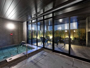 An indoor swimming pool area with glass walls, a digital clock, and a seating area with chairs. - Daiwa Roynet Hotel Akita-ekimae (Akita)