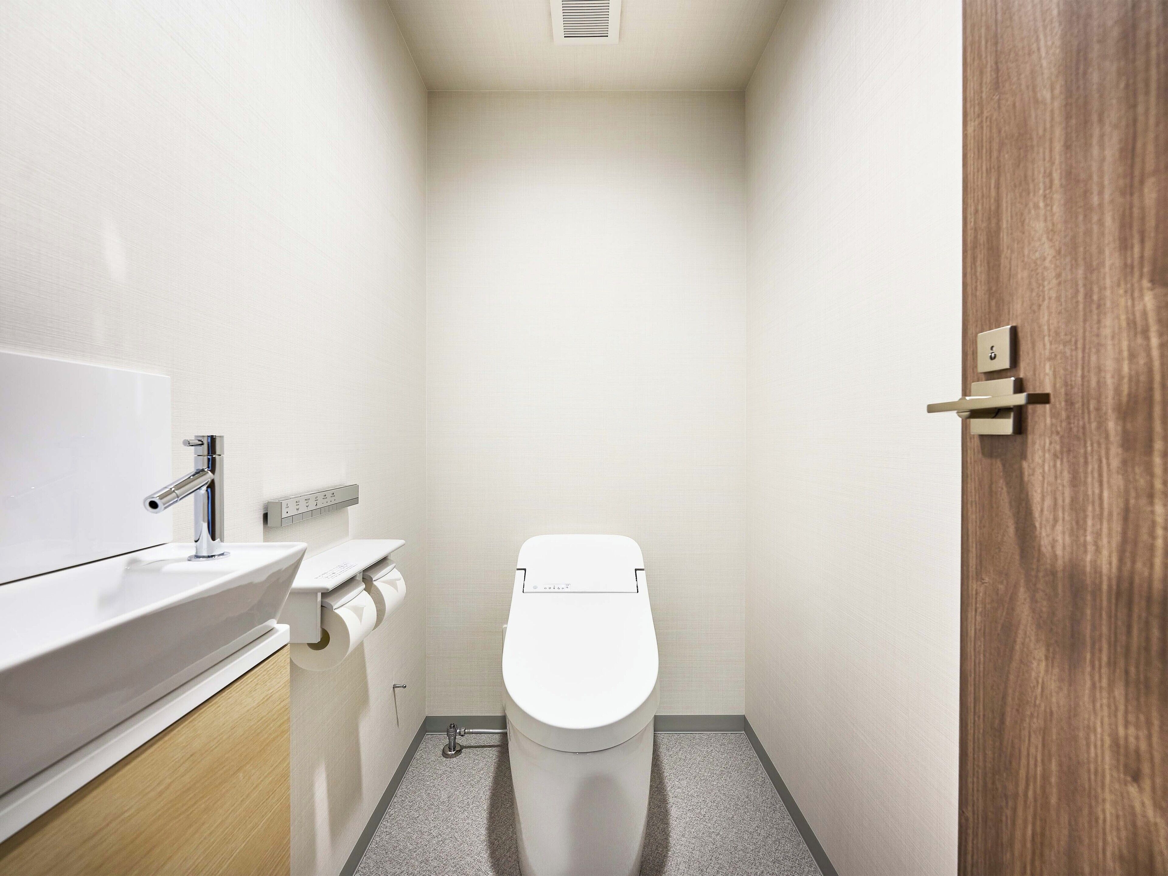 Ein kleines, modernes Badezimmer mit Toilette, Waschbecken und Spiegel.
