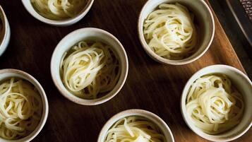 Multiple bowls of pasta arranged on a wooden surface.