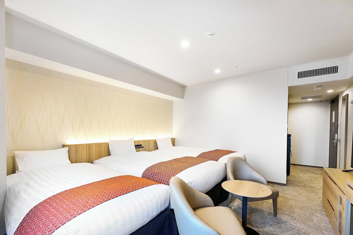 Ein Hotelzimmer mit zwei Betten, einem kleinen runden Tisch und einer Sitzecke.