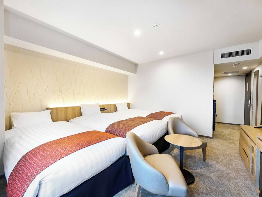 A hotel room with two beds, a small round table, and a seating area.