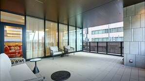 Un lobby moderno de hotel con un balcón amplio, ventanas grandes y mobiliario contemporáneo.