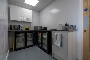 A kitchen with white cabinets, a microwave, a coffee maker, and a refrigerator.