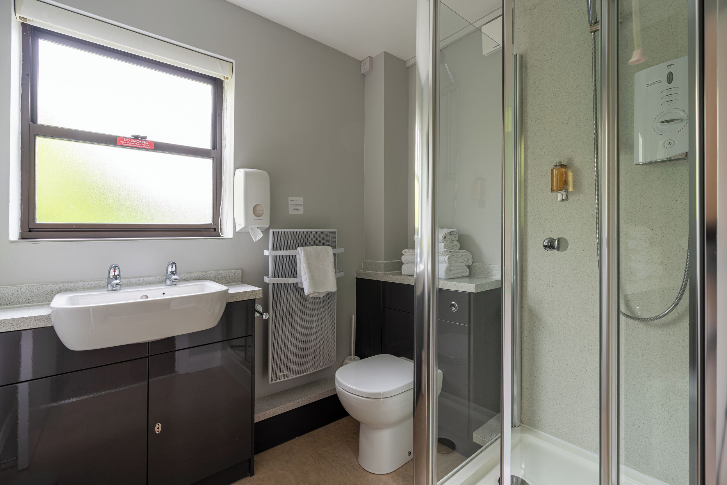 Baño con lavamanos, inodoro y cabina de ducha de vidrio.