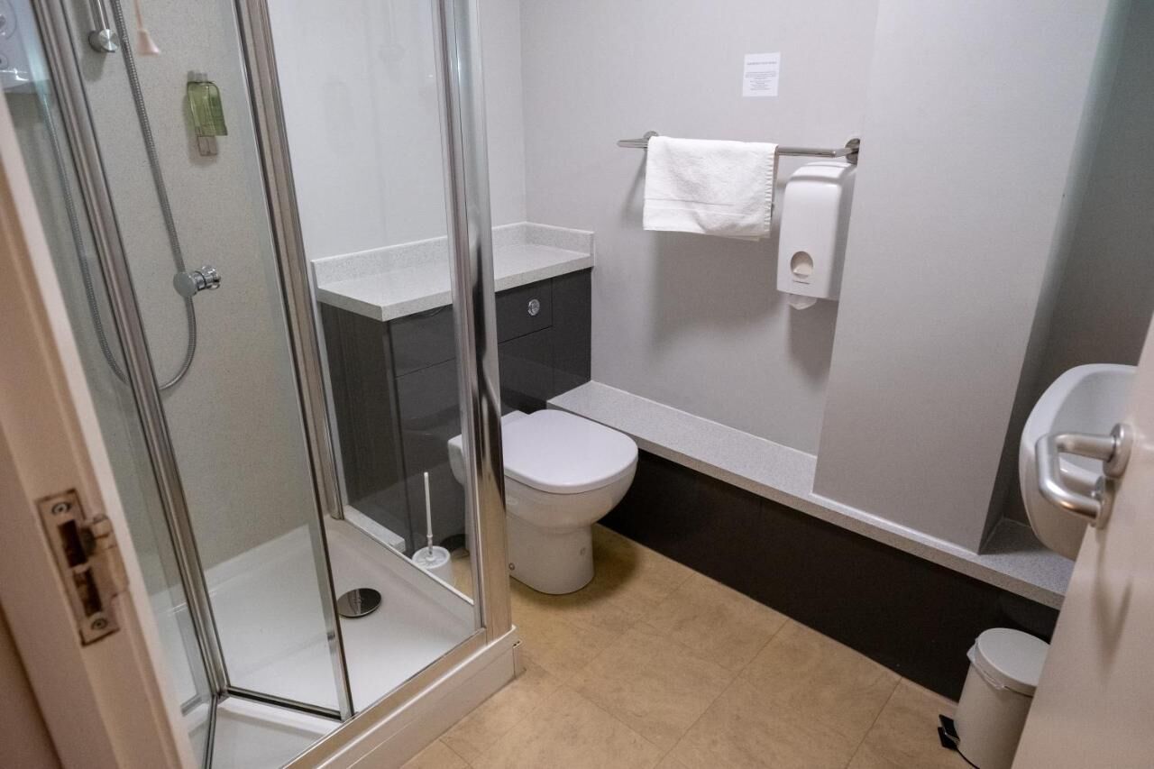 A modern bathroom with a glass-enclosed shower, a toilet, and a sink.