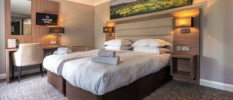 A hotel room with a large bed, a desk, a chair, a TV, and a painting on the wall.