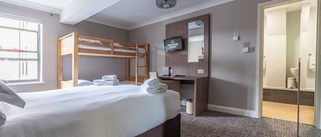 Ein Hotelzimmer mit Etagenbett, Schreibtisch, Fernseher und angrenzendem Badezimmer.