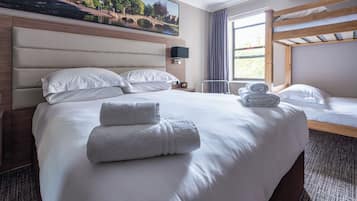 A hotel room with a large bed, a smaller bed, a TV, and a painting of a bridge.