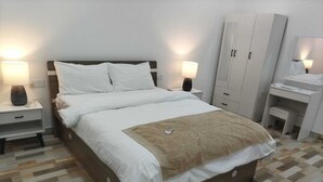 Una camera da letto ordinata con un letto grande, due comodini, un armadio e una scrivania con una sedia.