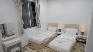 Una camera da letto con due letti, un comodino con una lampada, una piccola panca, uno specchio e una finestra con tende.