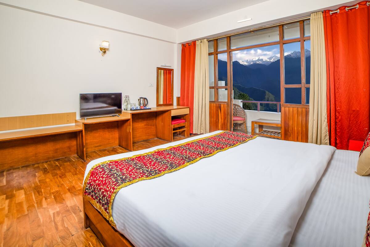 Une chambre d’hôtel avec un lit, un bureau, une télévision et une fenêtre avec des rideaux.