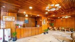A wooden reception area with a reception desk, potted plants, wicker furniture, and a clock on the wall. - Hotel Chiminda Pelling (Gyalshing)