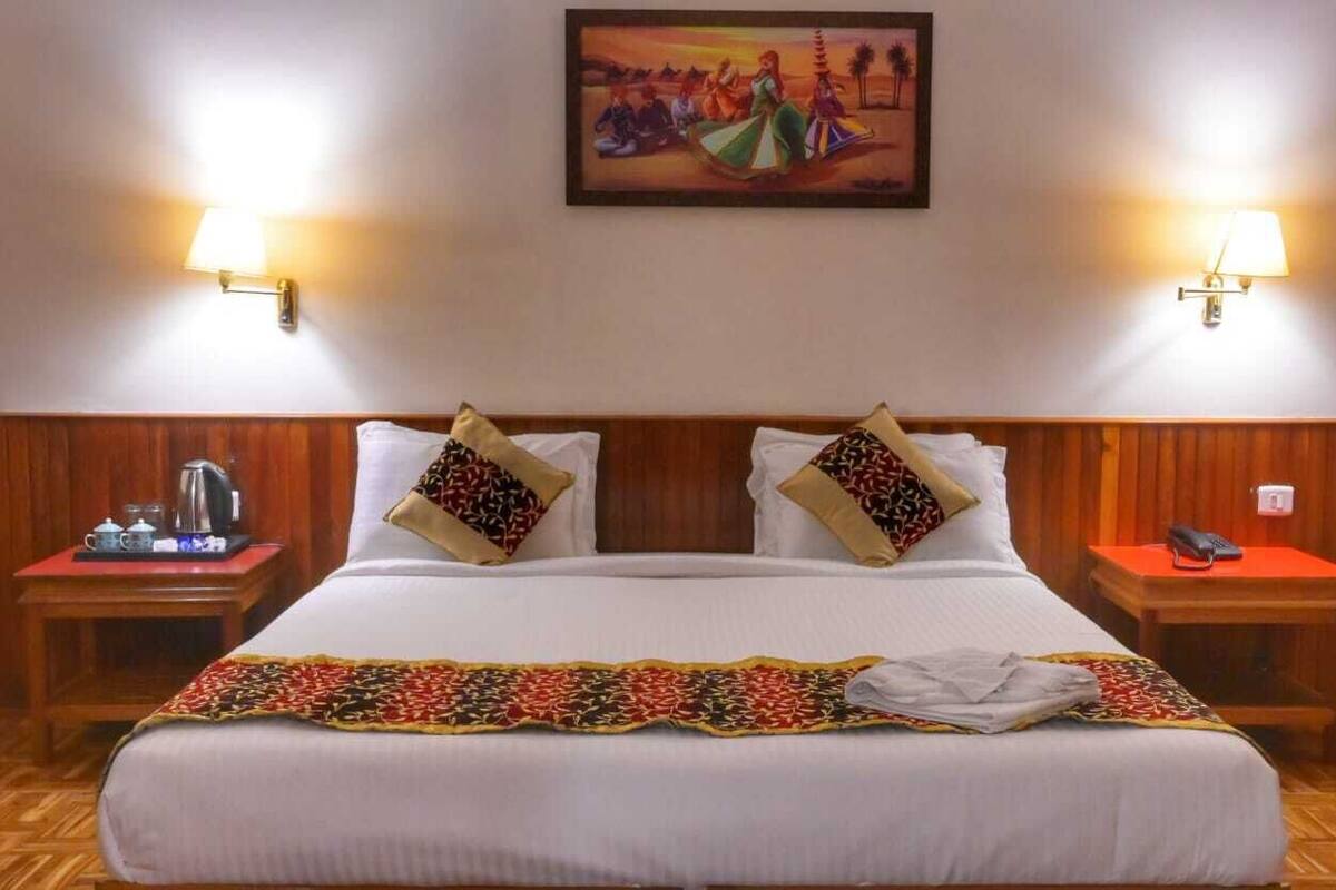 Une chambre d’hôtel avec un grand lit, deux tables de chevet, un tableau au mur et une tête de lit en bois.