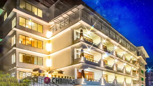 A multi-story hotel with a prominent "CHIMINDA" sign, outdoor seating, and a well-lit facade. - Hotel Chiminda Pelling (Gyalshing)