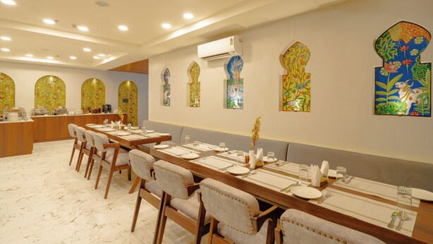 A dining area with a long table set for multiple guests, surrounded by chairs. - Alokah Kashi (Varanasi)