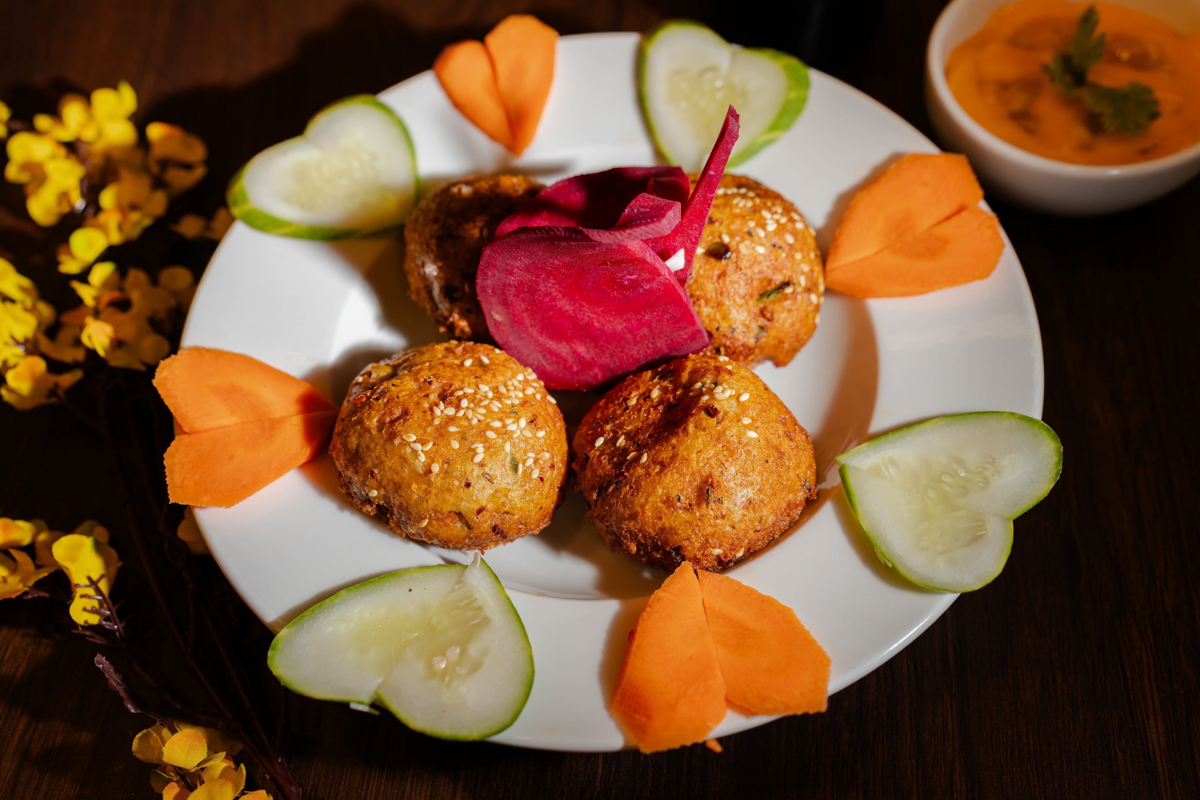 A plate of food with breaded balls, cucumber slices, and carrot slices.