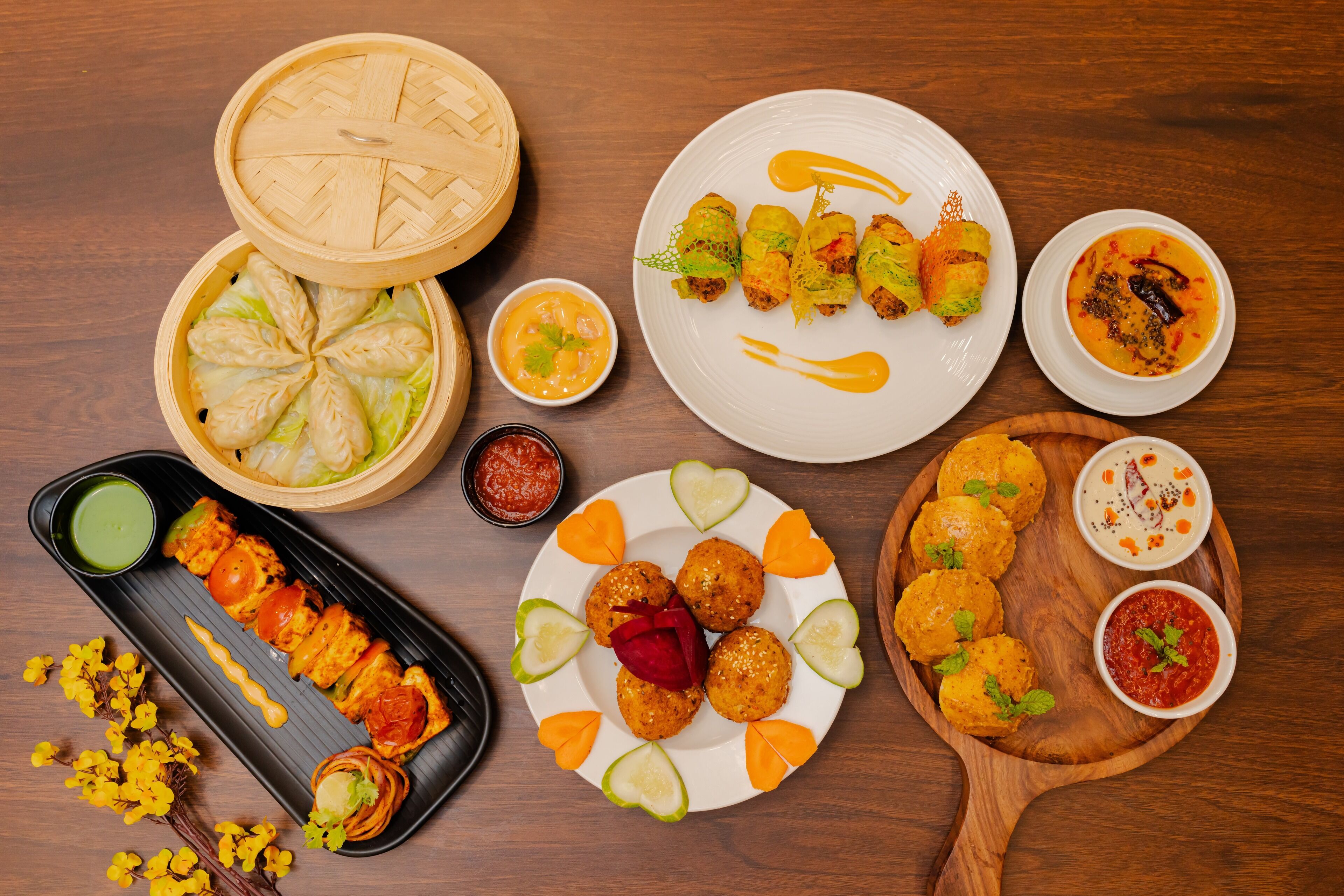 Un assortiment de plats comprenant des raviolis, des brochettes de viande et une assiette décorée de garnitures en forme de cœur.