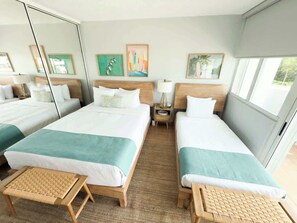 A hotel room with two beds, a large mirror, artwork on the walls, and a view of the outdoors.