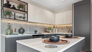 A modern kitchen with a central island, built-in shelves, and a sleek backsplash.