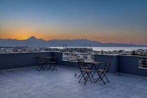 Terraza en la azotea con vistas a la ciudad y montañas al atardecer.