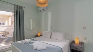 A hotel room with a bed, two bedside tables with lamps, a round mirror, and a balcony view.