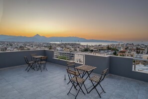 Eine Dachterrasse mit Blick auf eine Stadtlandschaft und Berge bei Sonnenuntergang.
