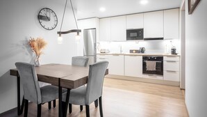 Una cucina moderna con mobili bianchi, un frigorifero in acciaio inossidabile e un forno a microonde.