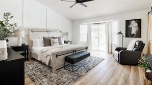 A bedroom with a large bed, a ceiling fan, a black leather chair, and a horse-themed painting. - Scottsdale Escape by LuxeKey | 4BDs Near Mayo Clinic & Kierland w/Pool (Scottsdale)
