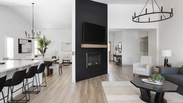 A modern living room with a fireplace, a dining area with a long table and chairs, and a black accent wall with a flat-screen TV. - Scottsdale Escape by LuxeKey | 4BDs Near Mayo Clinic & Kierland w/Pool (Scottsdale)