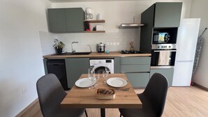 A compact kitchen with a dining area, featuring a dishwasher, stove, oven, and a coffee maker. - Longanea 1 (Saint Pierre)