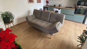 A modern kitchen with a grey sofa, a washing machine, and a microwave. - Longanea 1 (Saint Pierre)
