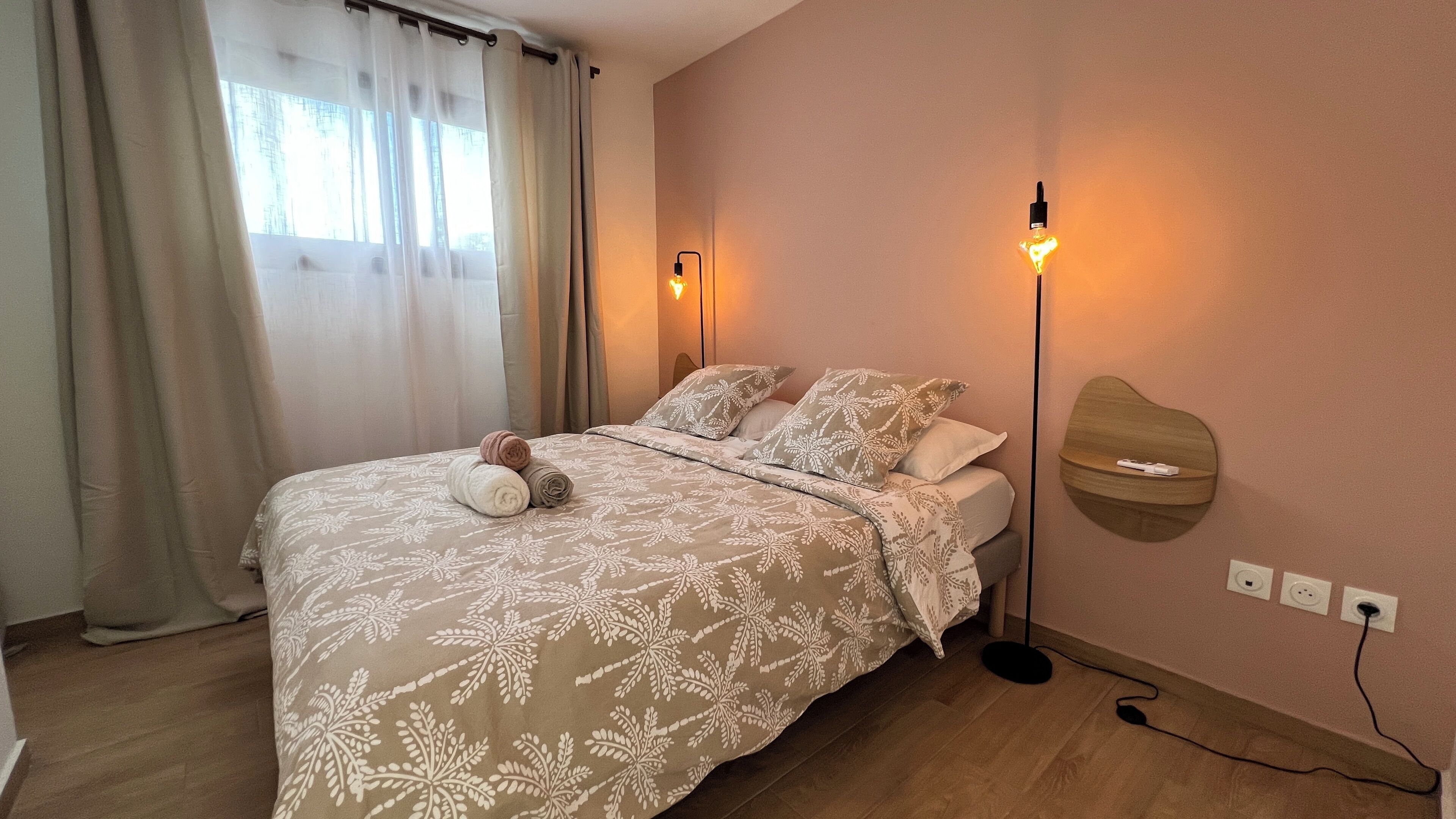 A neatly made bed with patterned bedding, a bedside lamp, and a wall-mounted light fixture.