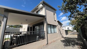 A modern two-story house with a balcony, large windows, and a visible air conditioning unit. - Longanea Residence Entière (Saint Pierre)