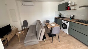 A compact living space with a sofa, dining table, and kitchenette. - Longanea Residence Entière (Saint Pierre)