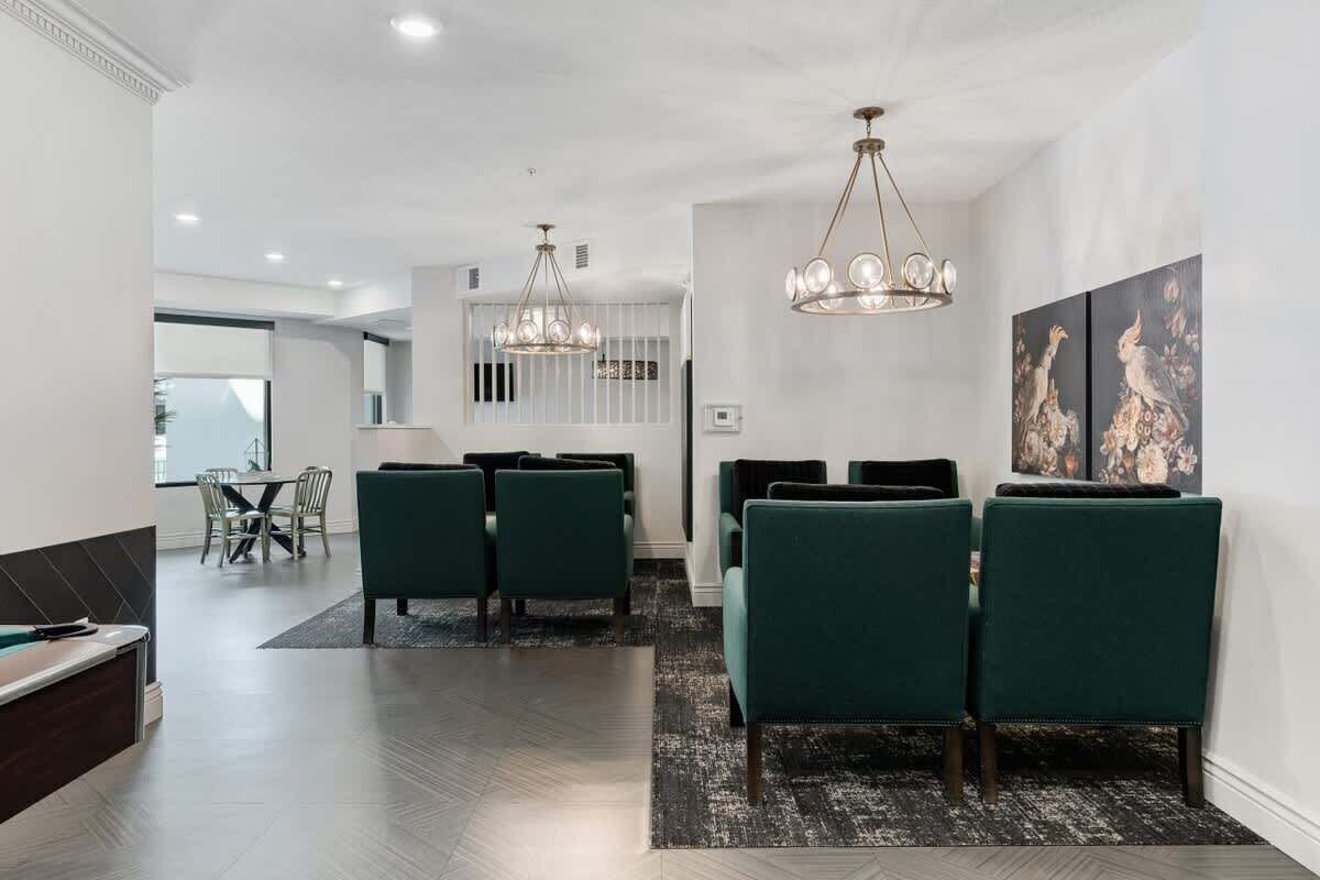 Un comedor moderno con una mesa larga, sillas tapizadas en verde y dos candelabros.