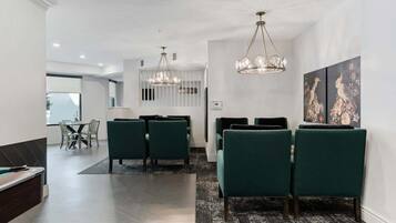 Un comedor moderno con una mesa larga, sillas tapizadas en verde y dos candelabros.