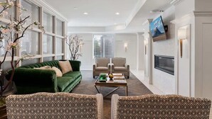Un salon spacieux avec un canapé vert, des fauteuils à motifs, une table basse et une cheminée.
