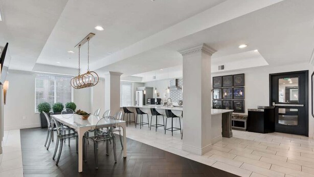 A modern kitchen with a central island, bar stools, and a dining area with a glass table and chairs. - Stylish 2-Bedroom with Parking, Near Temple Square (Salt Lake City)