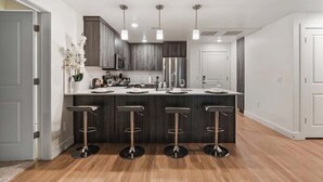 A modern kitchen with a central island, bar stools, and pendant lighting. - Stylish 2-Bedroom with Parking, Near Temple Square (Salt Lake City)