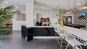 A modern kitchen with a black and white herringbone backsplash, white bar stools, and pendant lighting. - Stylish 2-Bedroom with Parking, Near Temple Square (Salt Lake City)