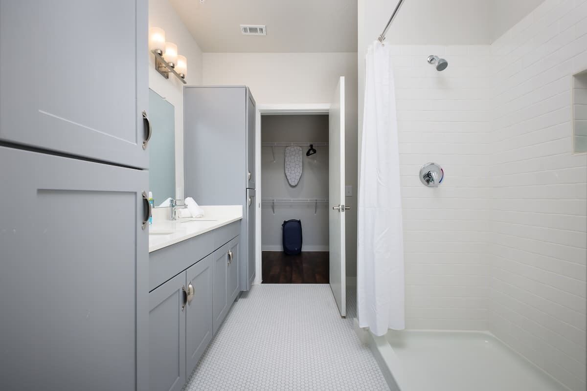 Un baño moderno con ducha a nivel, inodoro y armario de almacenamiento.