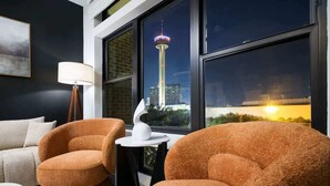 Una habitación moderna con dos sillones naranjas, una lámpara blanca y vistas a una torre por la noche.