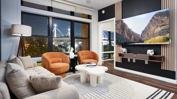 Una sala moderna con un ventanal grande, un sofá, dos sillones, una mesa de centro y un televisor montado.