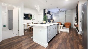 Cocina moderna con isla central, suelo de madera e iluminación colgante.