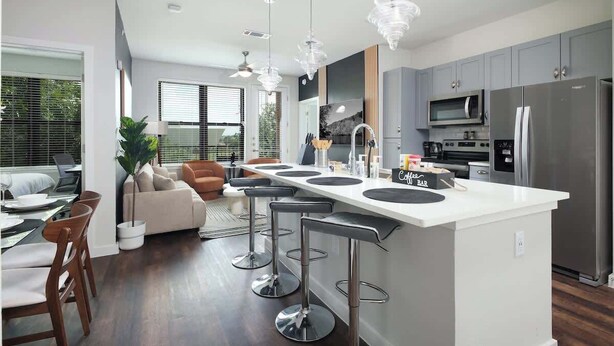 A modern kitchen with a central island, stainless steel appliances, and bar stools.