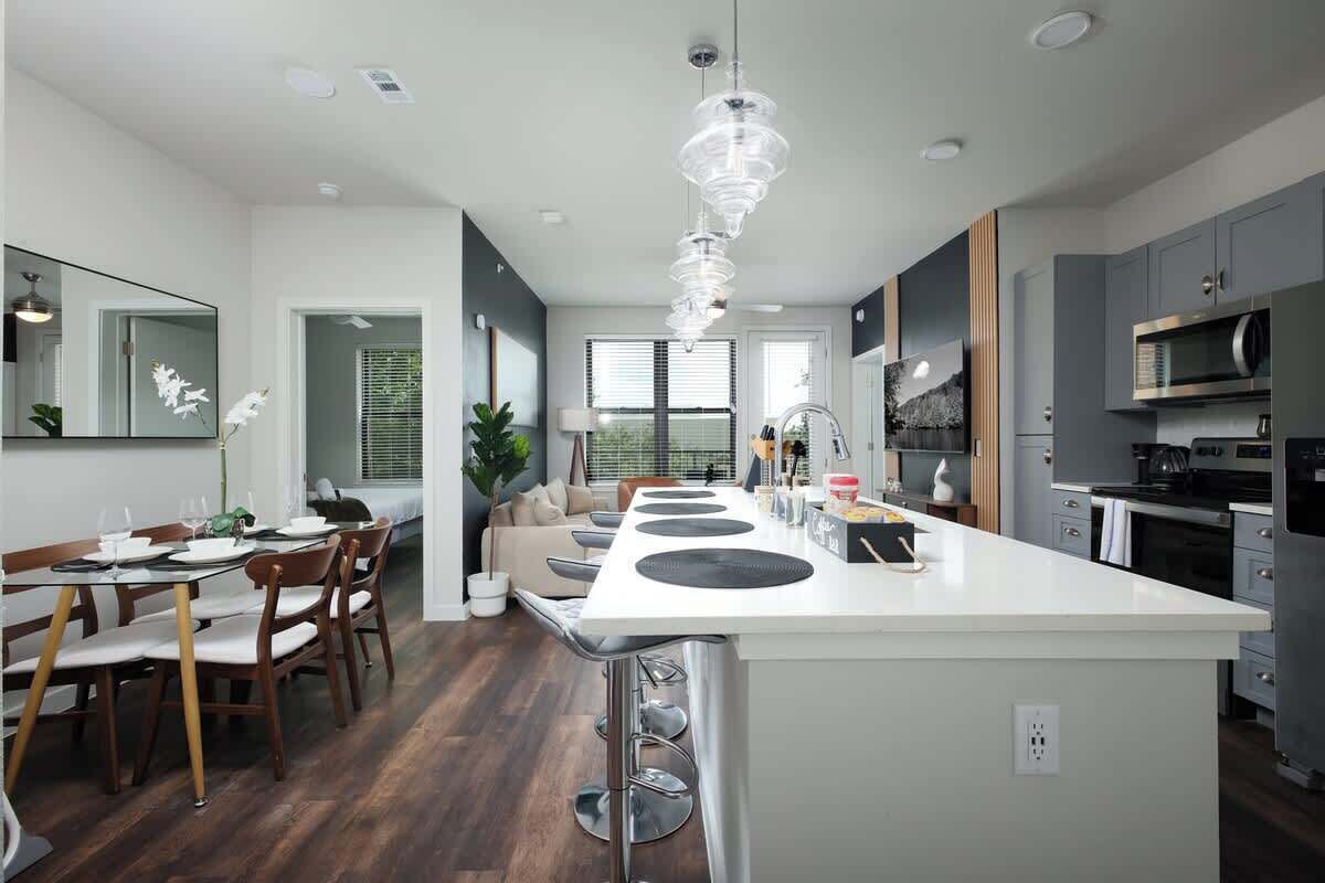 A modern kitchen with a central island, grey cabinets, and stainless steel appliances.