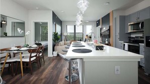A modern kitchen with a central island, grey cabinets, and stainless steel appliances.
