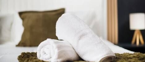 A neatly made bed with white linens and a brown throw blanket.