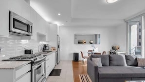 Cocina moderna con estufa, microondas y armarios. Hay un comedor con mesa y sillas.